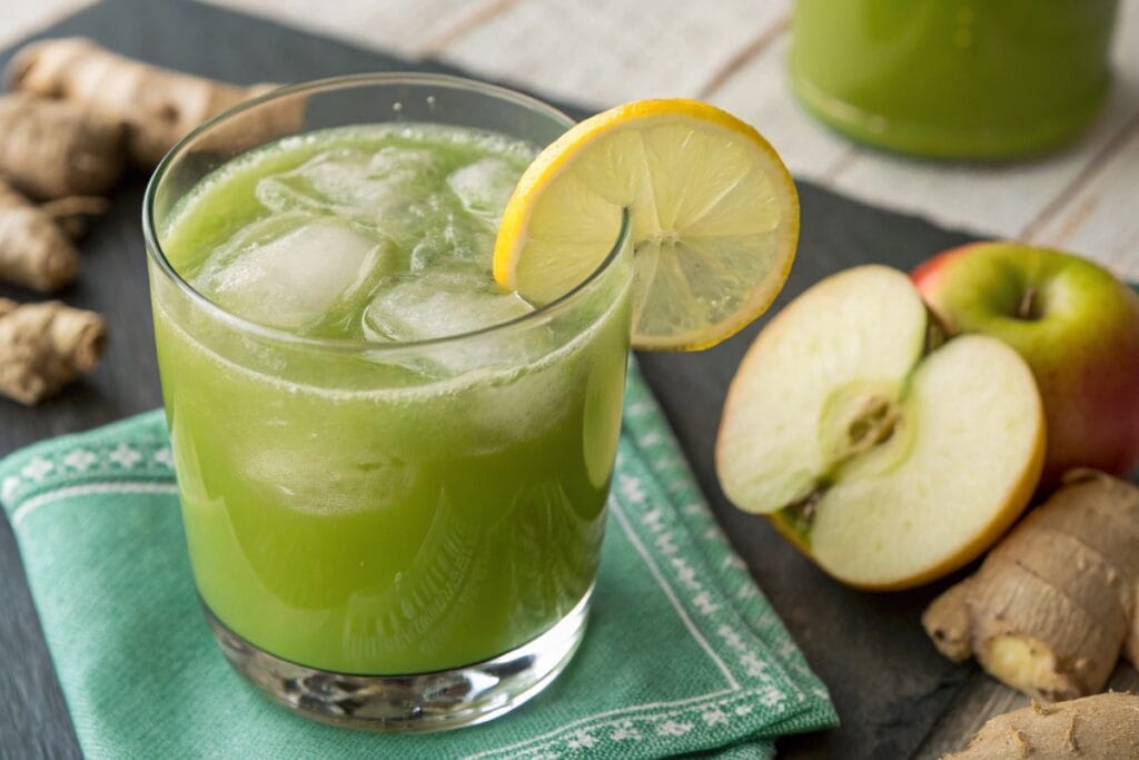 Single glass of green juicing recipes with lemon garnish