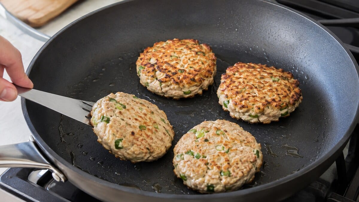 Golden tuna patties cooking in a lightly oiled nonstick skillet